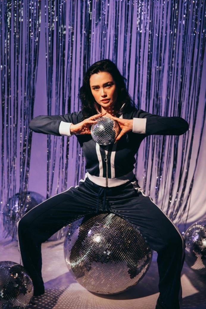 Photo by KoolShooters : https://www.pexels.com/photo/woman-in-a-tracksuit-holding-a-disco-ball-6982559/